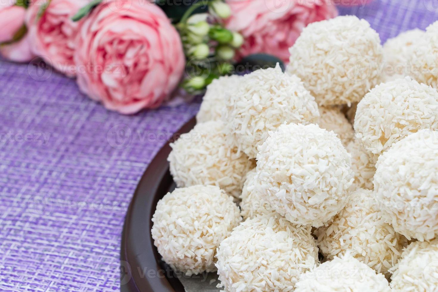 Homemade coconut candy on a background of pink flowers photo