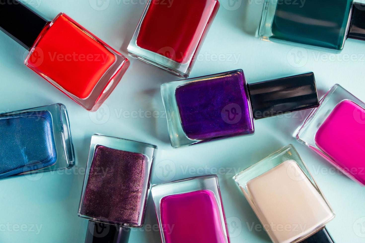 Group of bright colored nail polishes on blue background photo