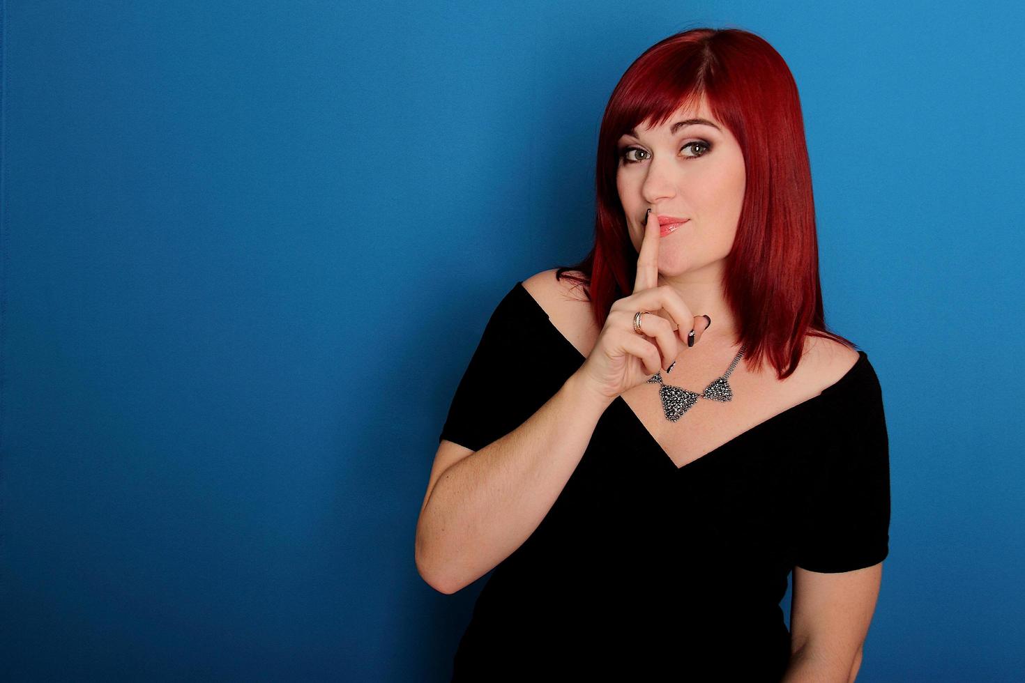 Woman with red hair holding finger to lip photo