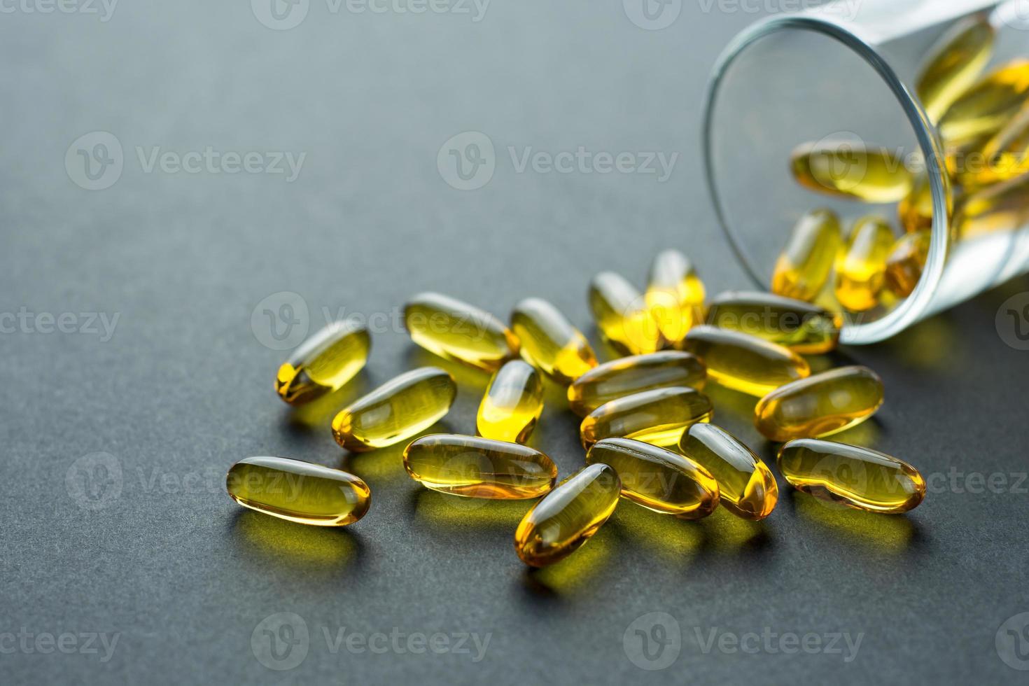 Fishoil capsules out of the small glass on black background with copy space photo