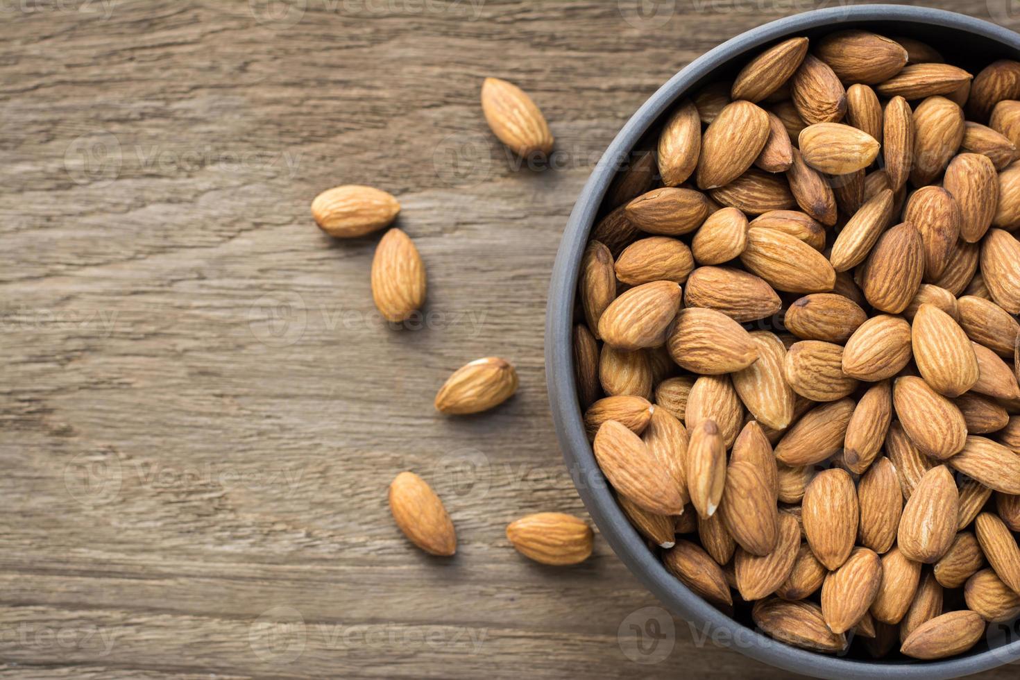 Top view of Almonds in porcelain bowl on wooden table with copy space photo