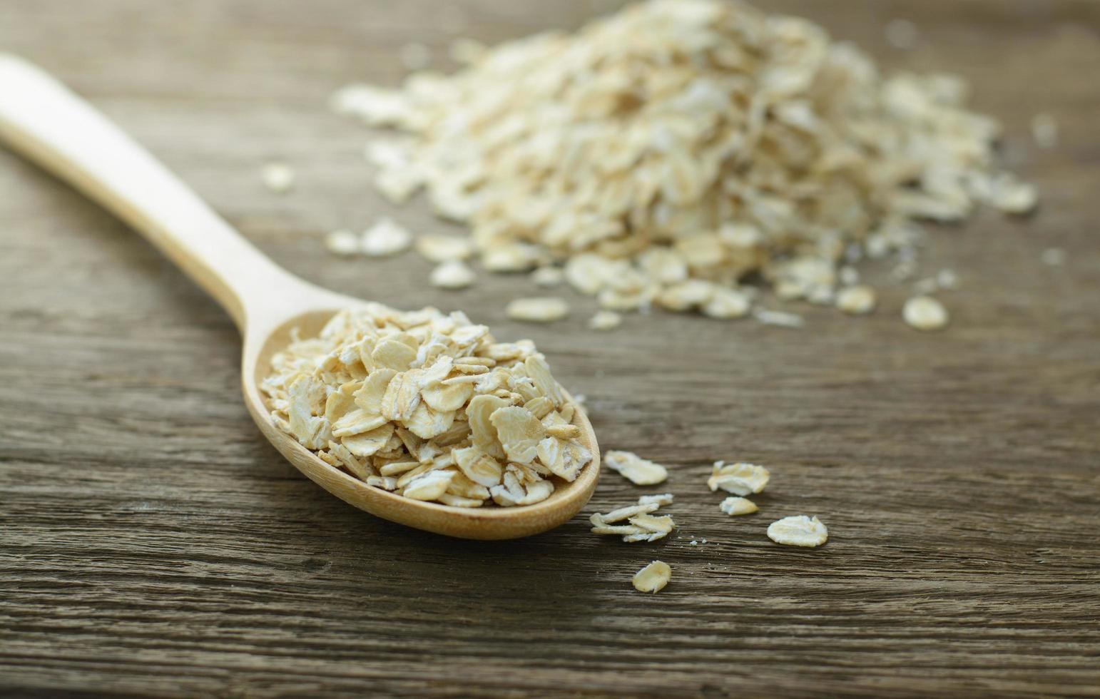 Copos de avena o avena en la cuchara de madera en la mesa de madera foto