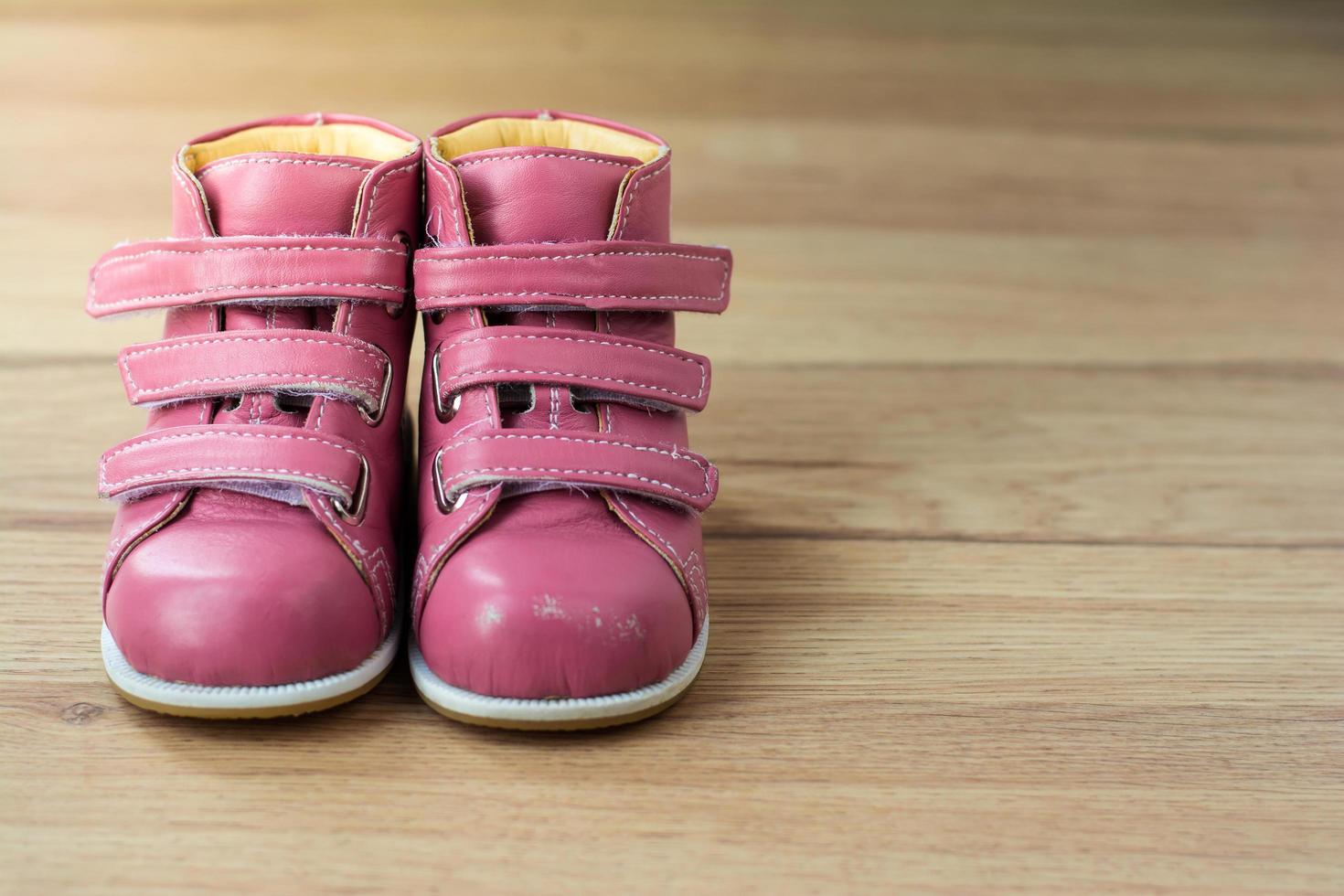 Pink Kids Shoes on wood background photo
