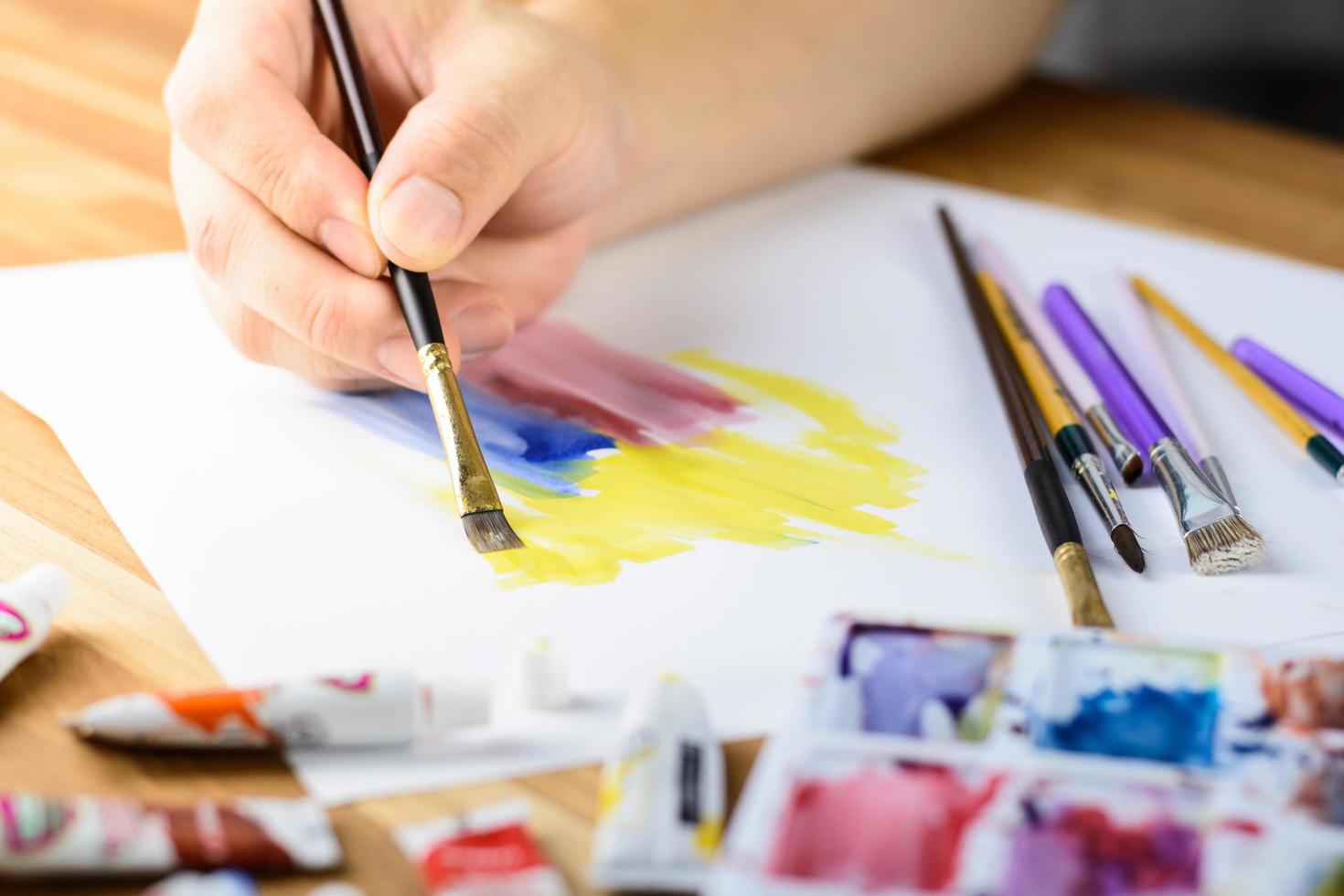 Close up of male artist hand painting water color with blured Palette with color foreground photo