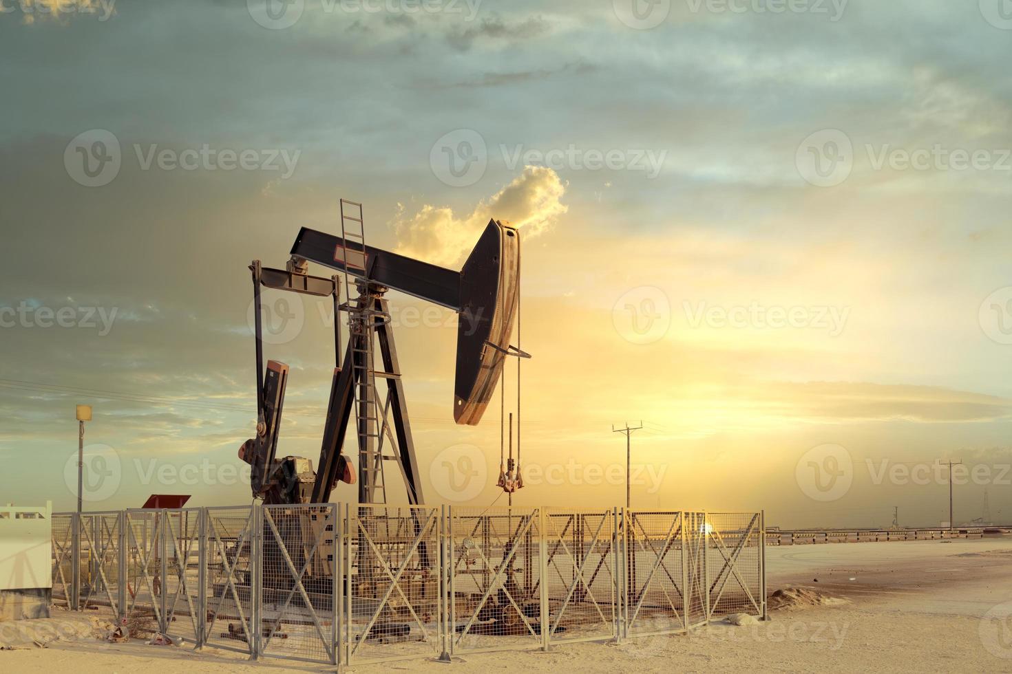 An oil pump jack with sunset in the background photo