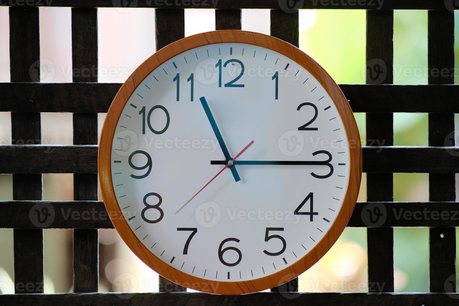 Reloj de pared sobre fondo de madera y concepto de tiempo foto