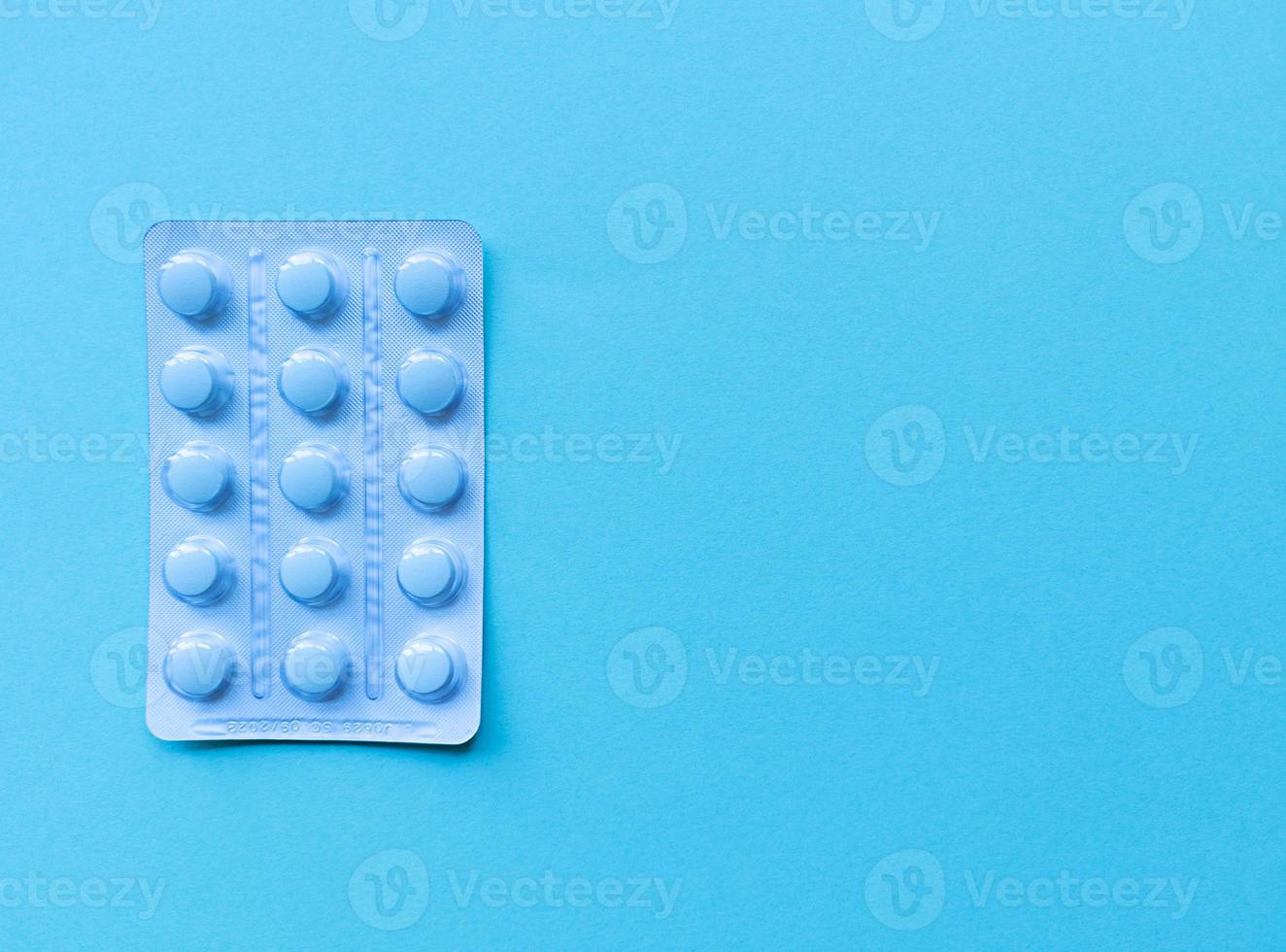 A blister of blue pills on blue background Monochrome simple flat lay with pastel texture with copy space Medical concept Stock photo