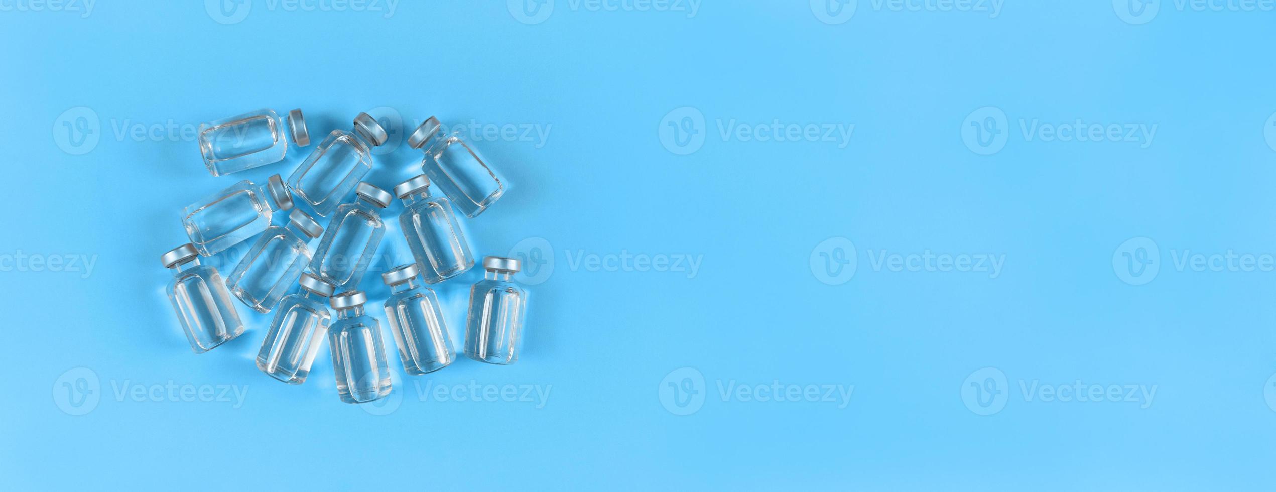 Lots of vials with liquid medicine on blue backdrop with copy space photo