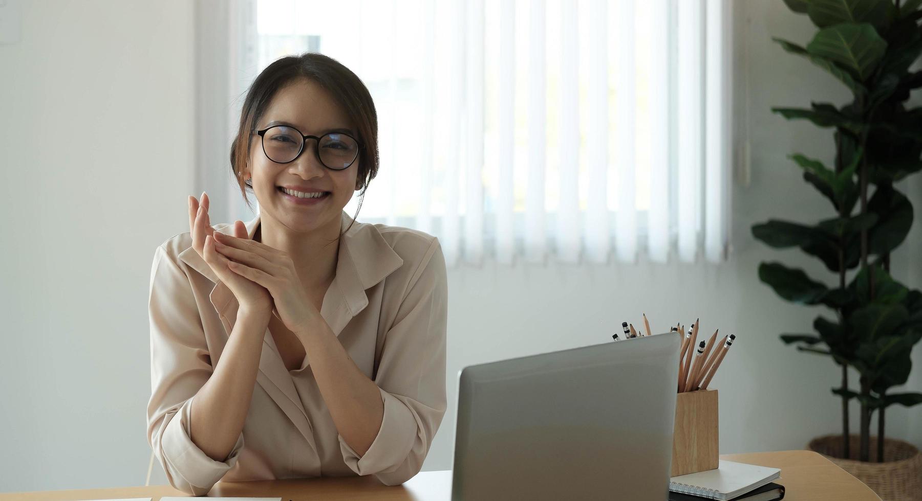 retrato, de, sonriente, mujer de negocios, sentar escritorio, en, el, oficina, trabajo en la computadora portátil foto