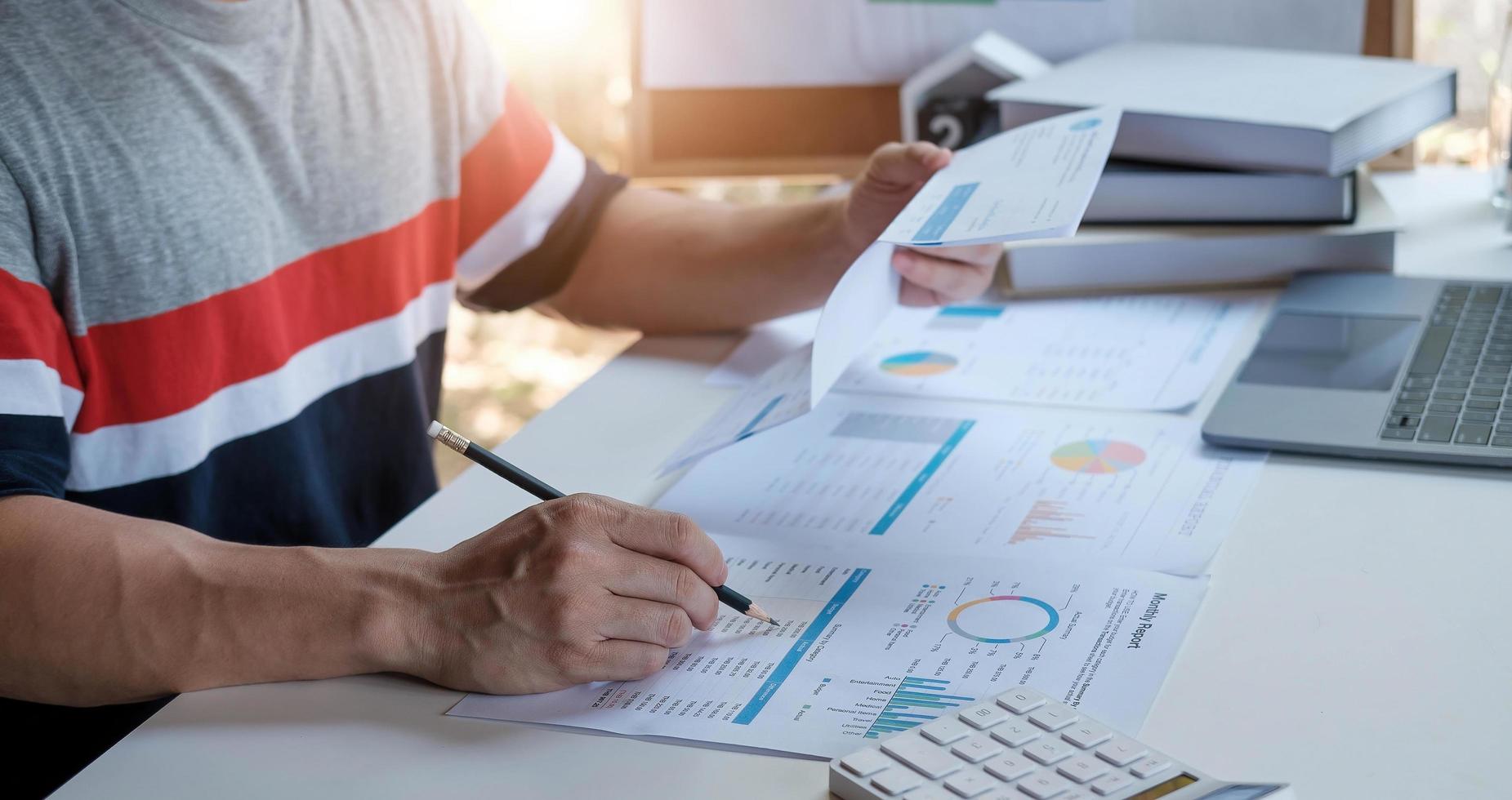 Un hombre que usa la calculadora para calcular facturas de gastos en su concepto de negocio en el lugar de trabajo foto