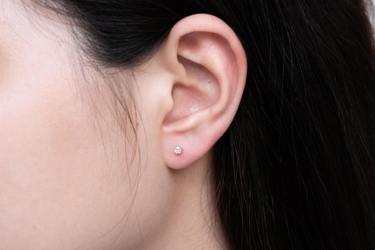 Pendiente de diamantes en la oreja de una mujer asiática. foto
