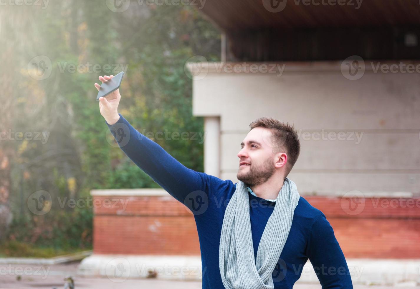 young man taking a picture with his cell phone in the park photo