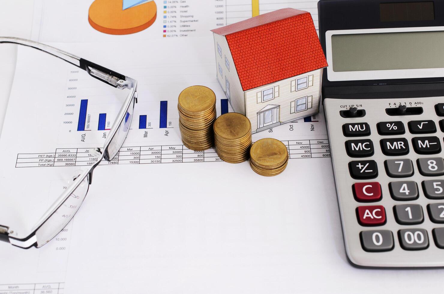 Home loans concept with close up coins stack and paper house and calculator and eyeglasses photo