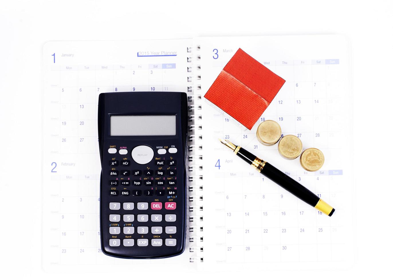 Concepto de planificación de préstamos hipotecarios con pluma estilográfica y calculadora y monedas y casa de papel en las páginas del libro de calendario foto