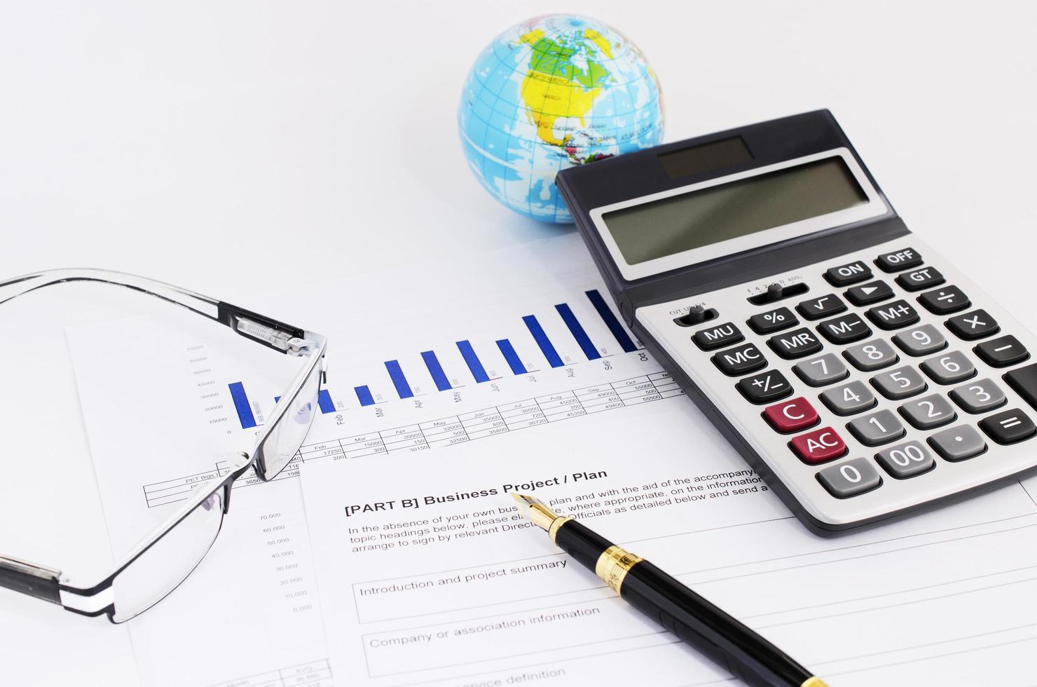 Business concept with close up fountain pen and calculator and eyeglasses on financial report photo