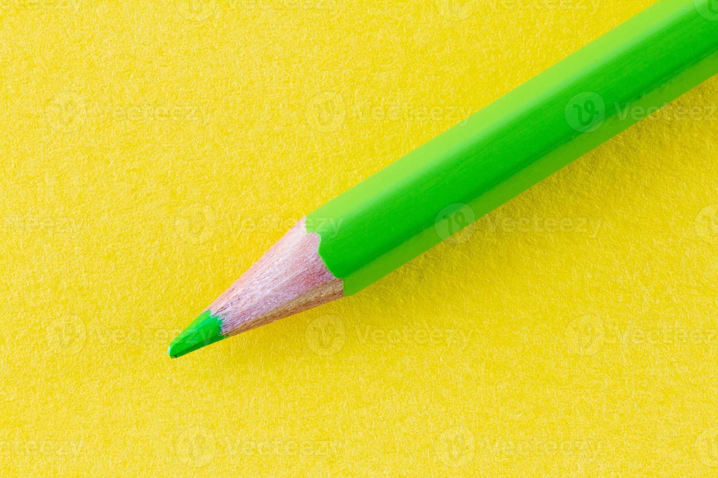 Green color pencil on yellow color paper arranged diagonally photo