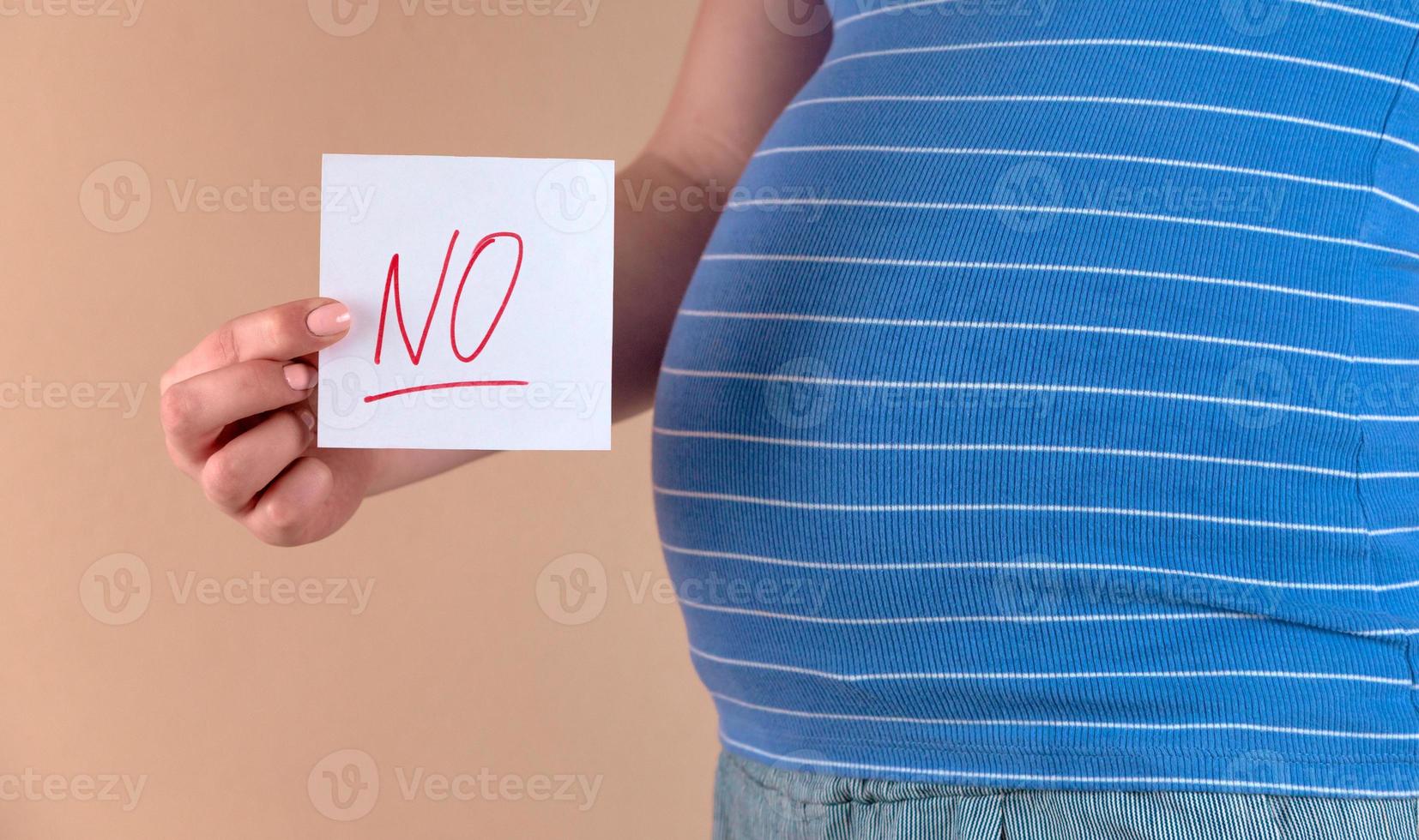 A close up view of the belly of a pregnant woman with the word NO photo