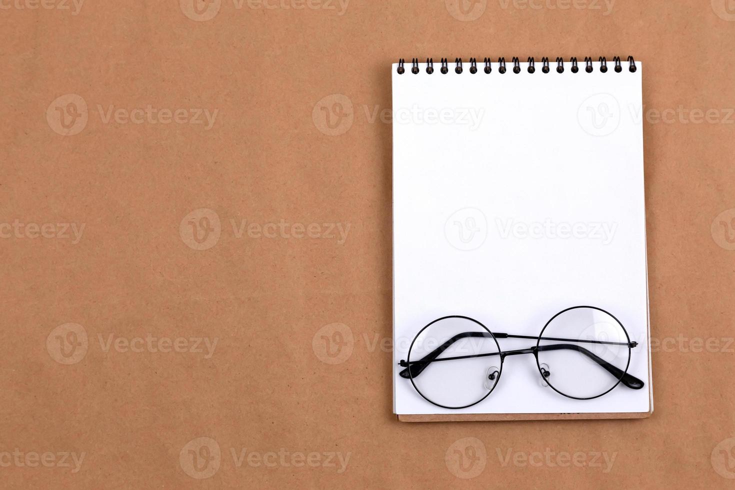 Flat lay top view of glasses and notepad on a beige background photo