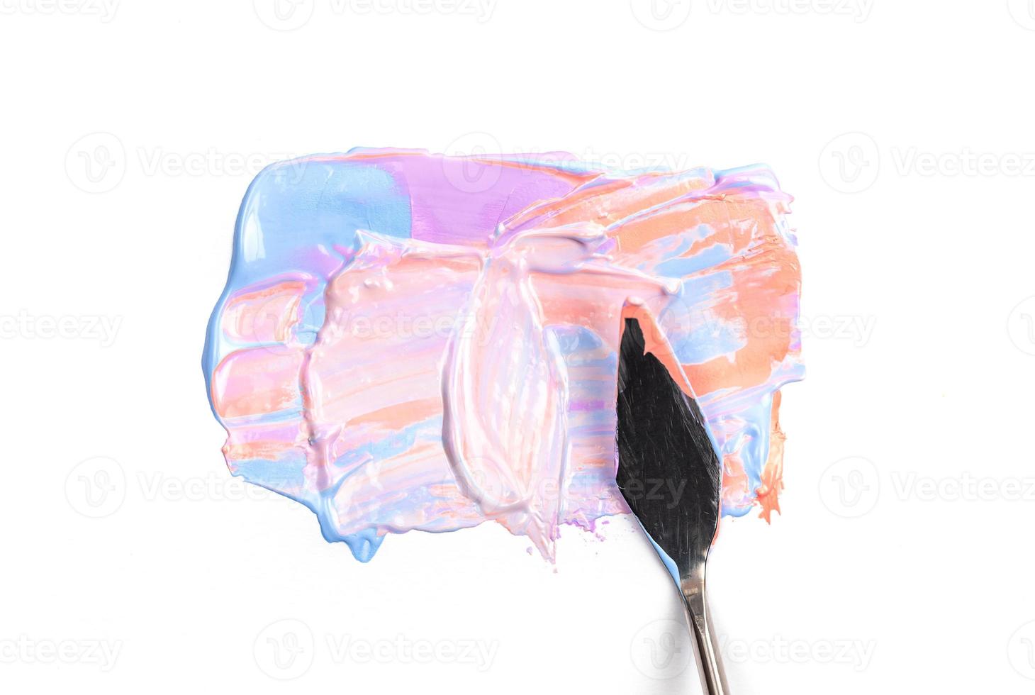 Una espátula de pintura aislada sobre un fondo blanco con rosa y violeta foto