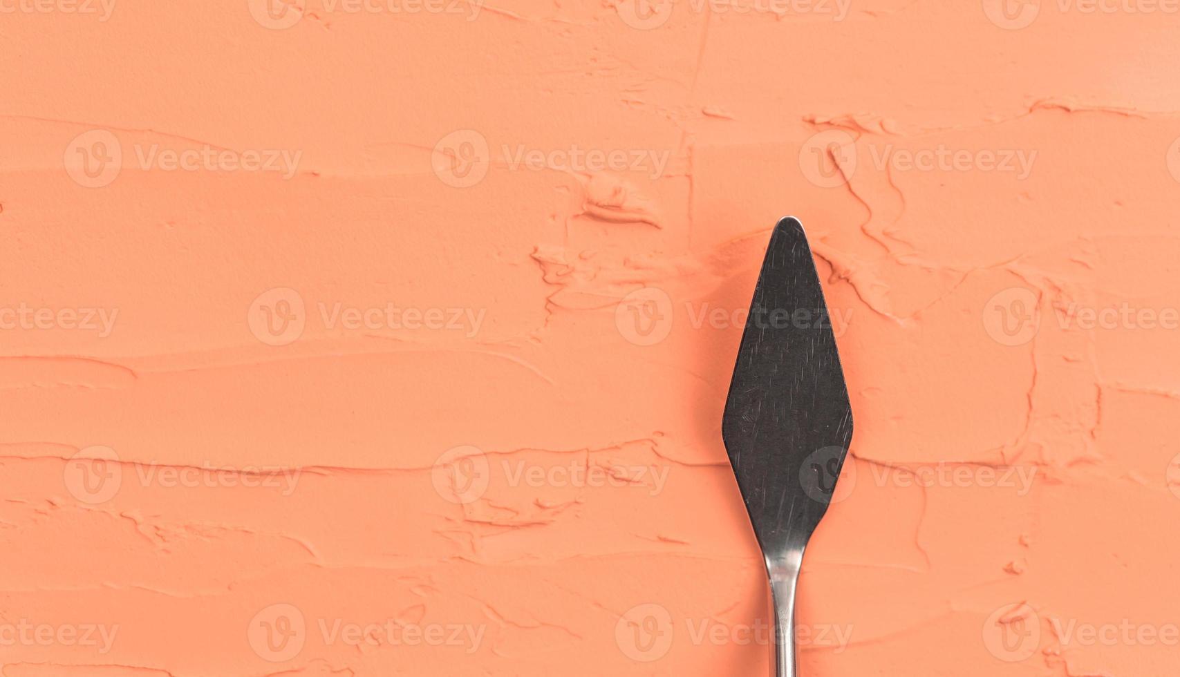 A painting palette knife isolated on a orange painted background painting with copy space photo