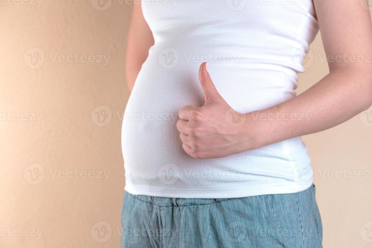 A close up view of the belly of a pregnant woman that shows a like sign photo