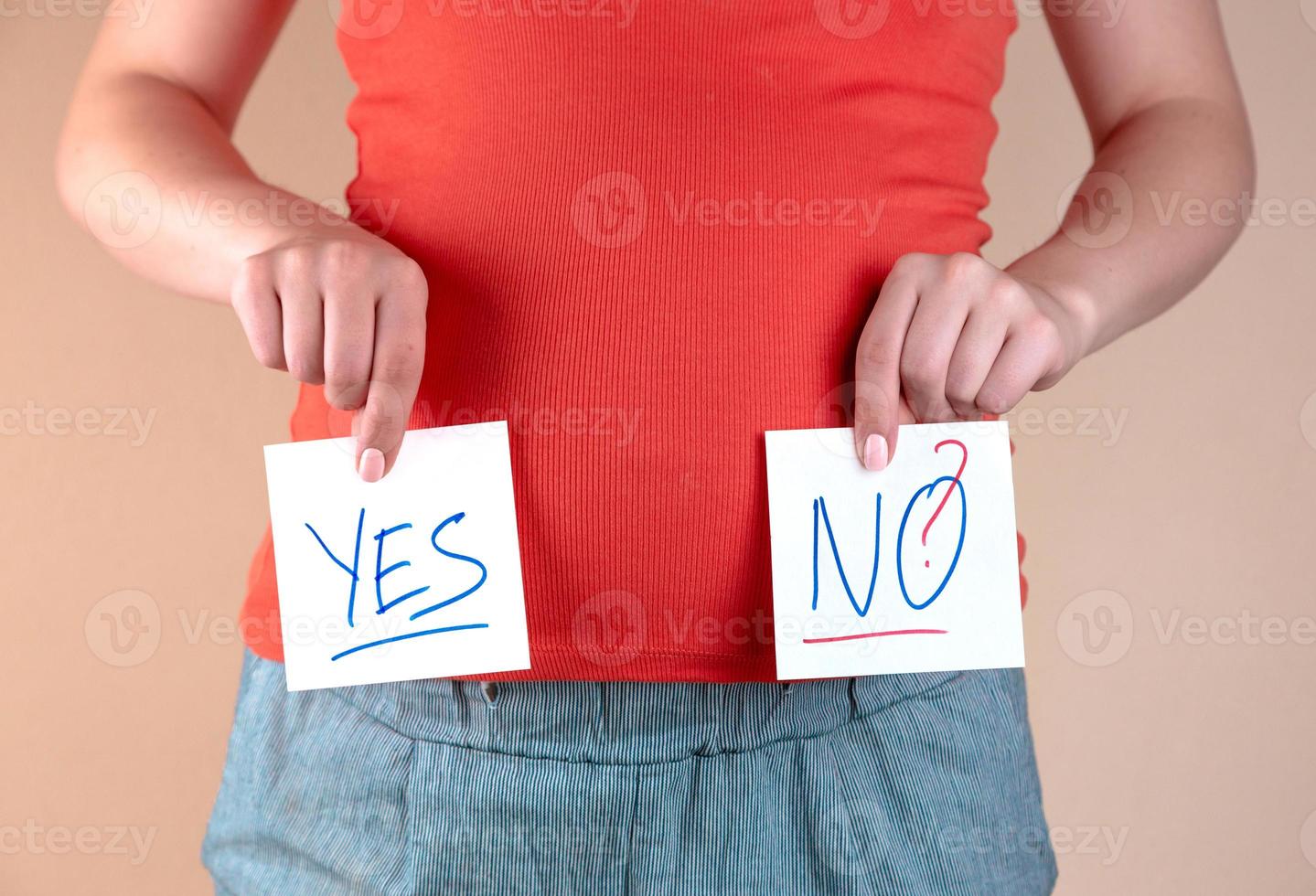 A close up view of the belly of a pregnant woman with two sheets with the inscriptions YES and NO photo