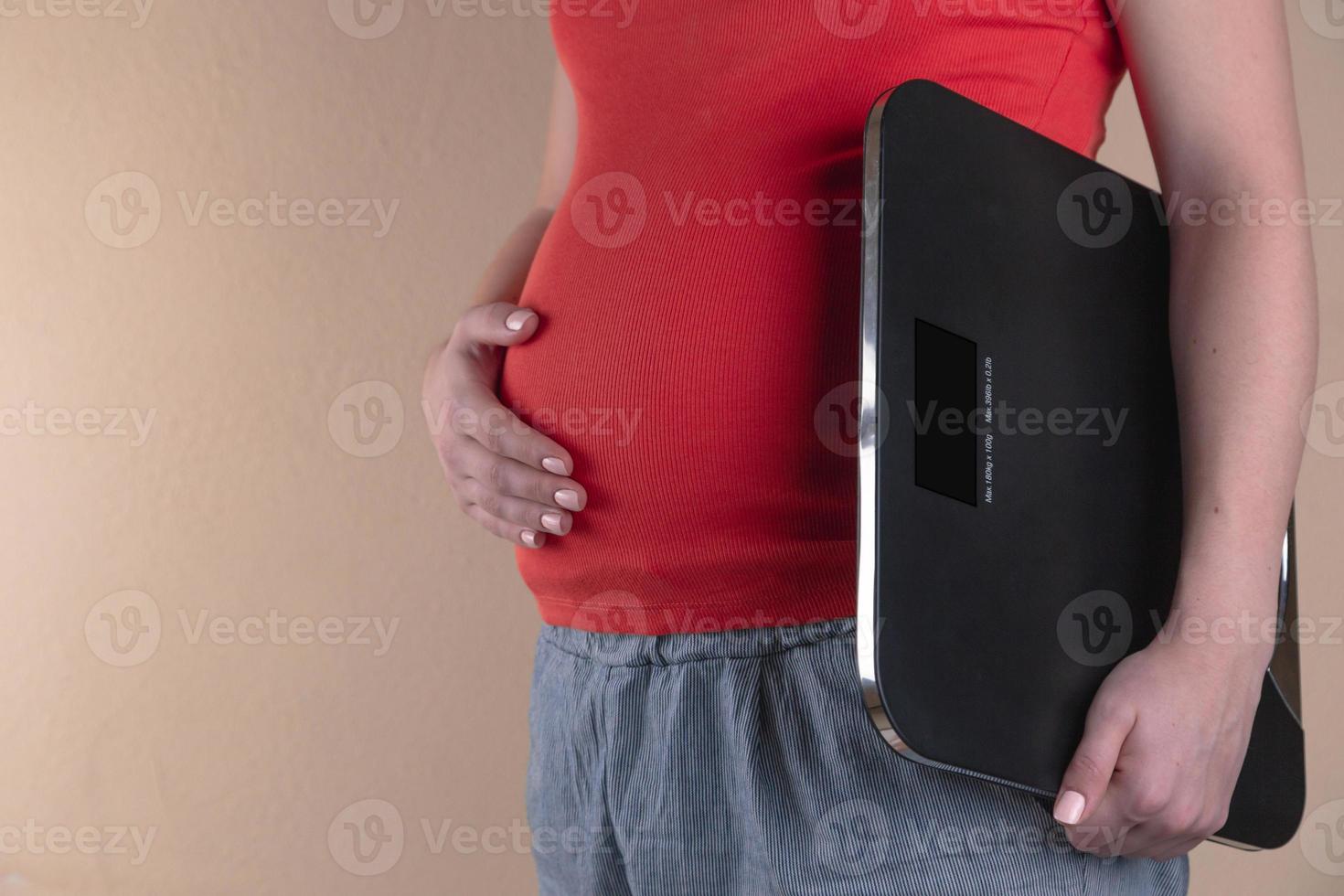 Una vista de cerca del vientre de una mujer embarazada en rojo. foto
