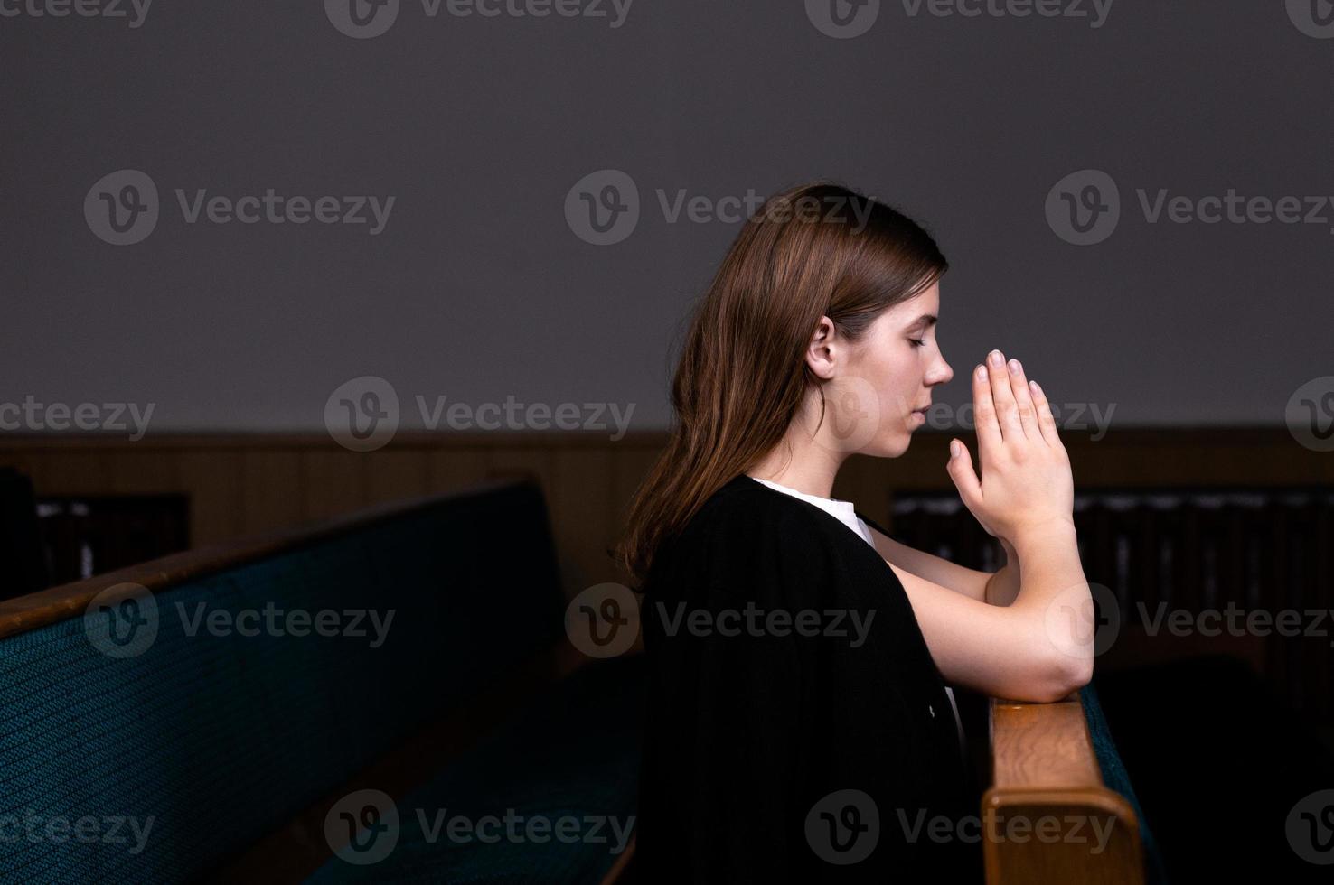 A Christian girl in white shirt is sitting and praying with humble heart in the church photo