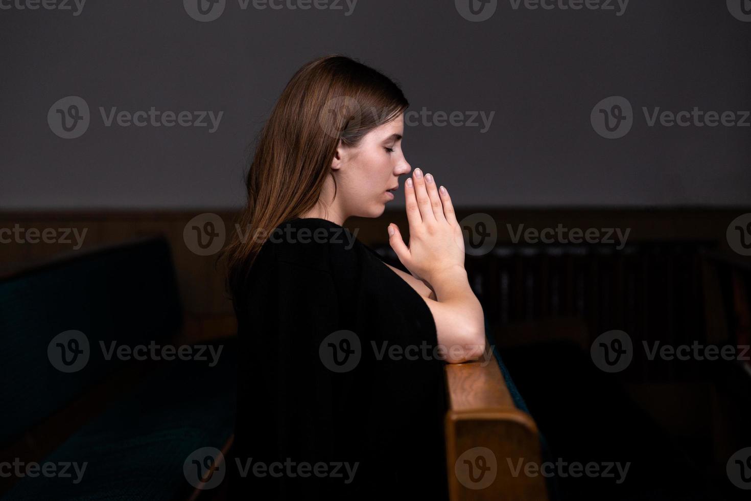 una niña cristiana con camisa blanca está orando con corazón humilde en la iglesia foto