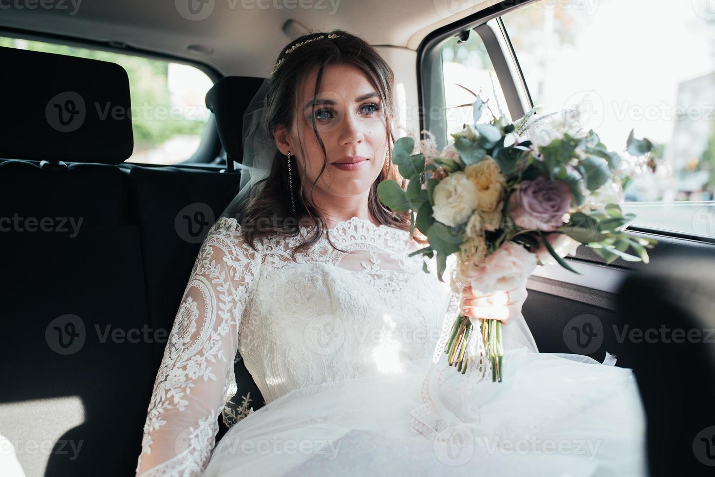 foto de la boda de la novia que está sentada en el coche con un ramo de flores