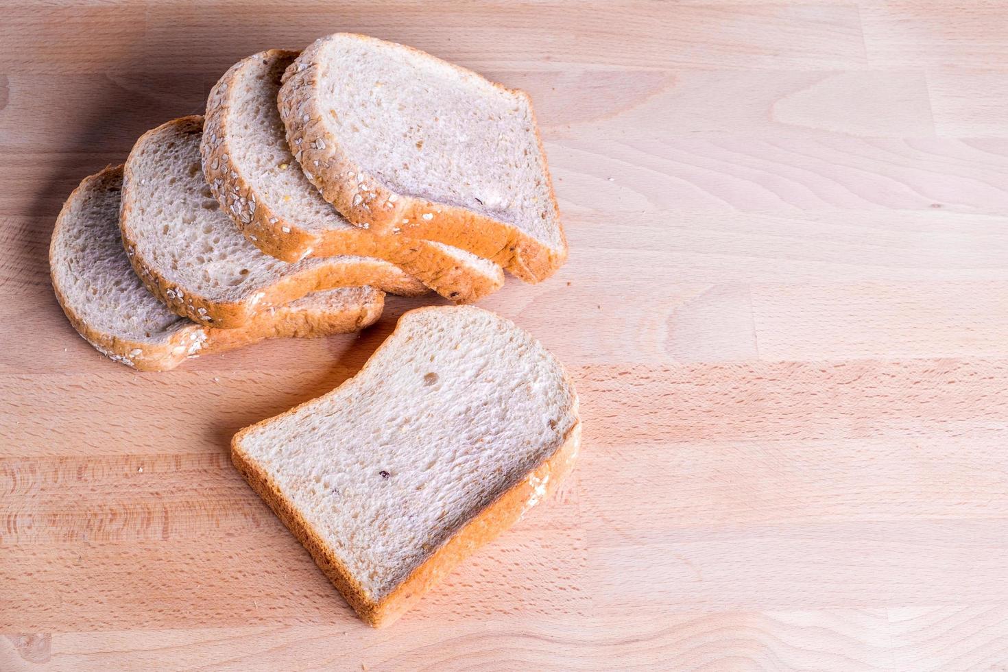 Rebanada de pan de trigo integral sobre fondo de piso de madera foto