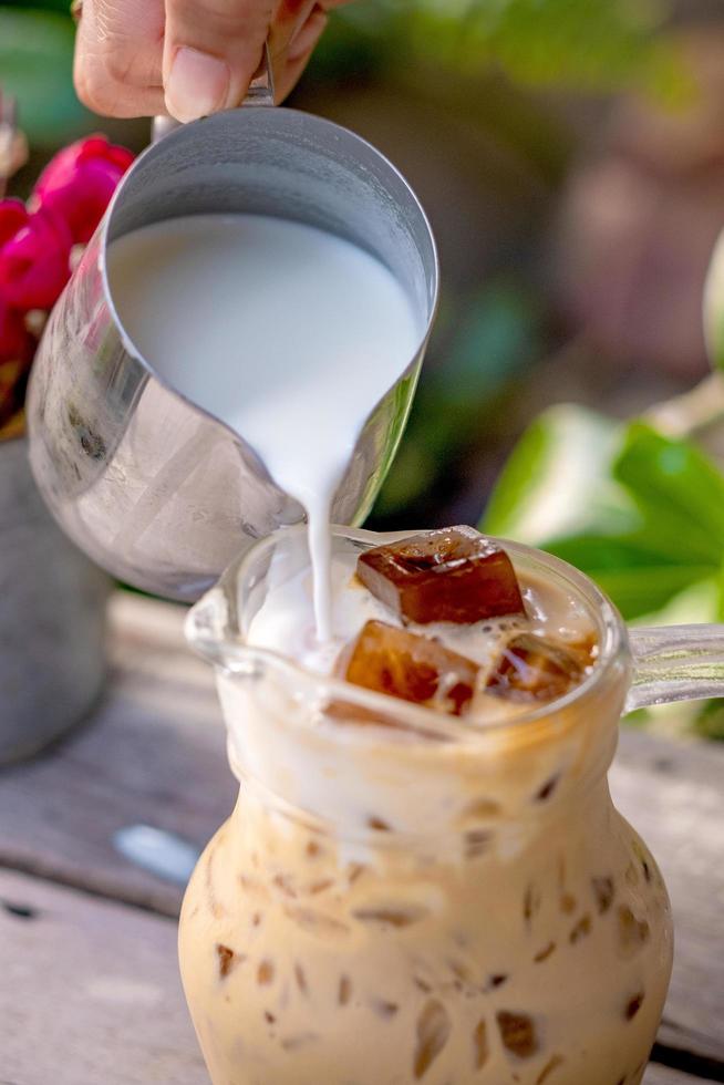 vertiendo leche en un vaso con café con leche y helado foto