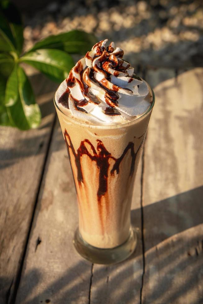 Coffee frappe with whipped cream on old wooden table in the morning sun photo