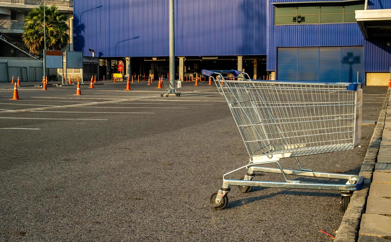 Shopping cart with traffic cone in store parking lot blue background photo