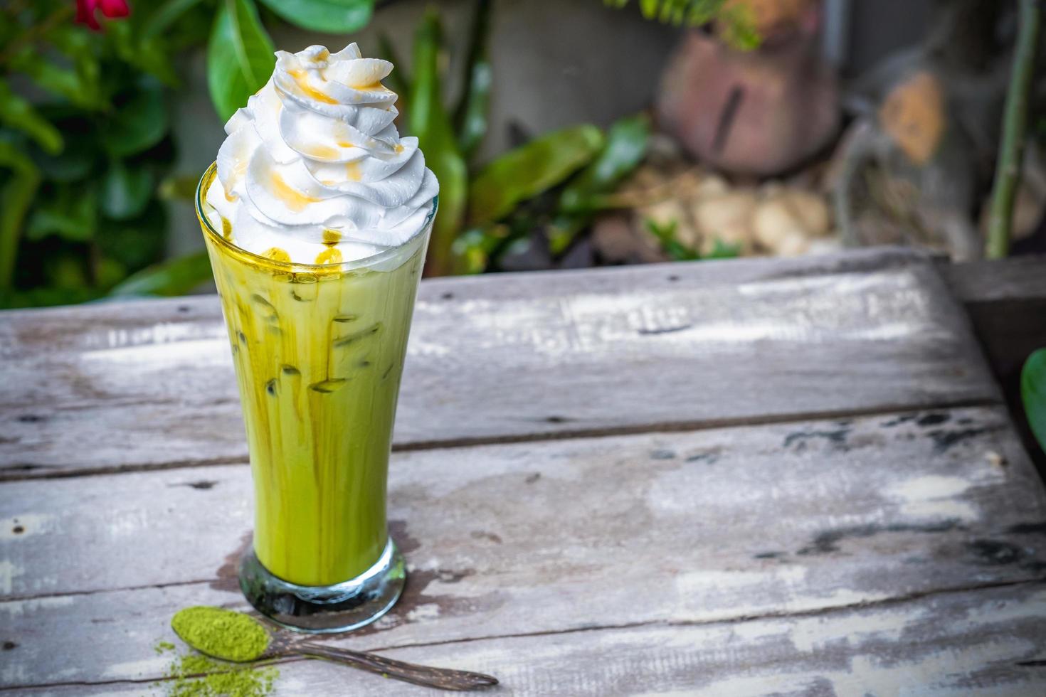 Ice matcha green tea with whipped cream on wooden table background photo