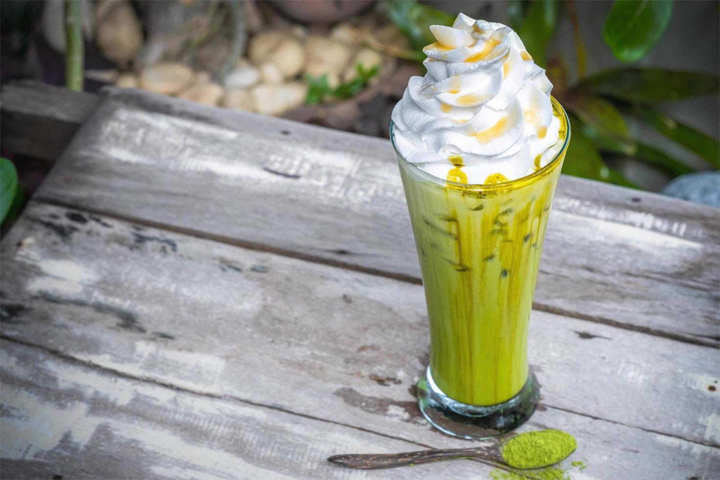 Ice matcha green tea with whipped cream on wooden table background