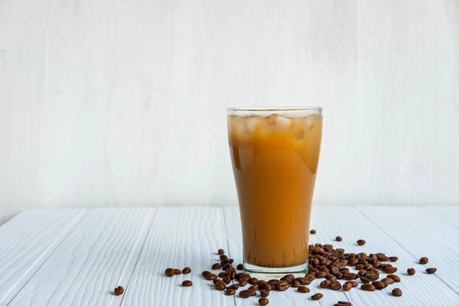 Café helado en un vaso sobre un fondo de madera blanca foto