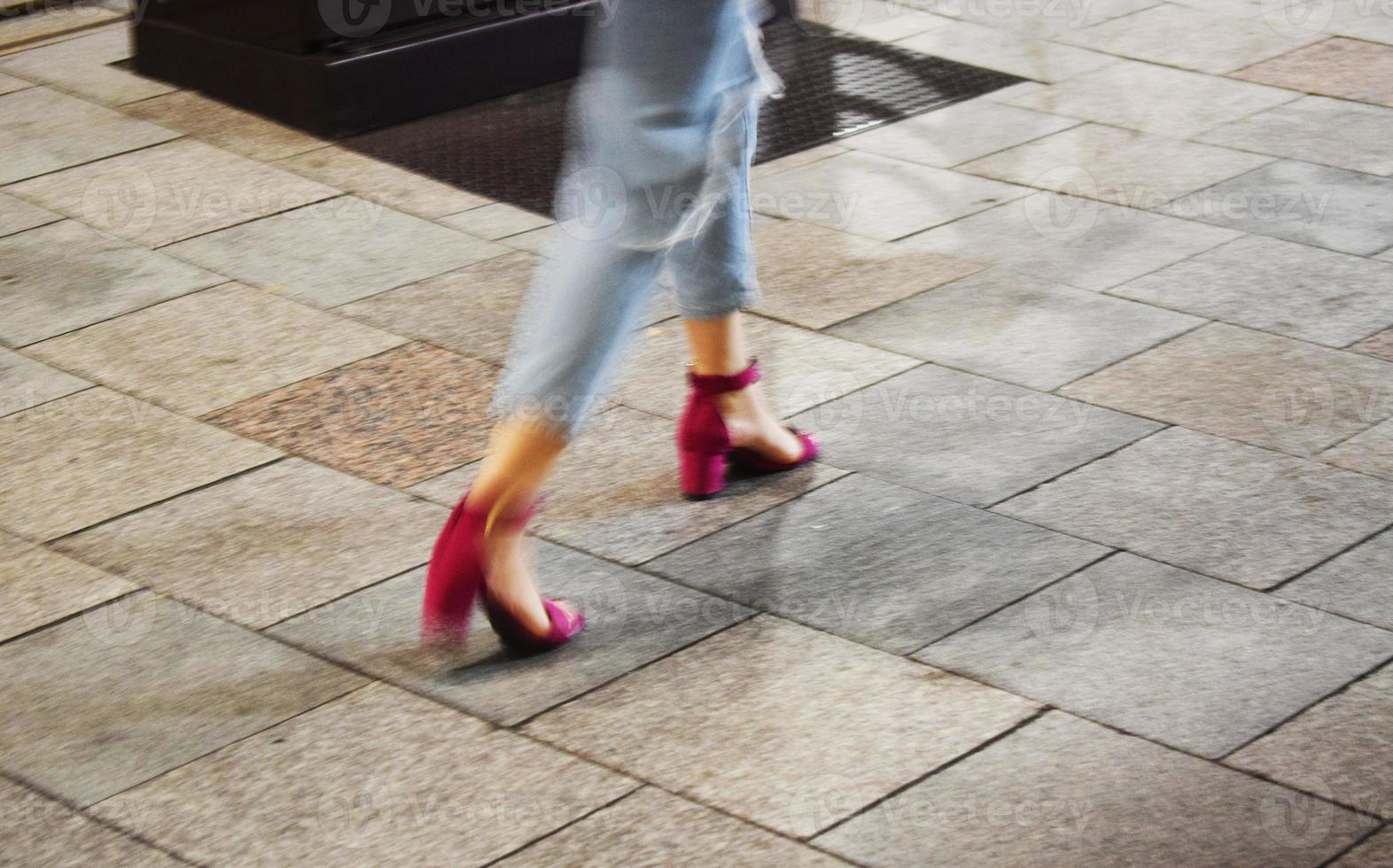 Walking woman wearing blue denim jeans and pair of pink sandals photo