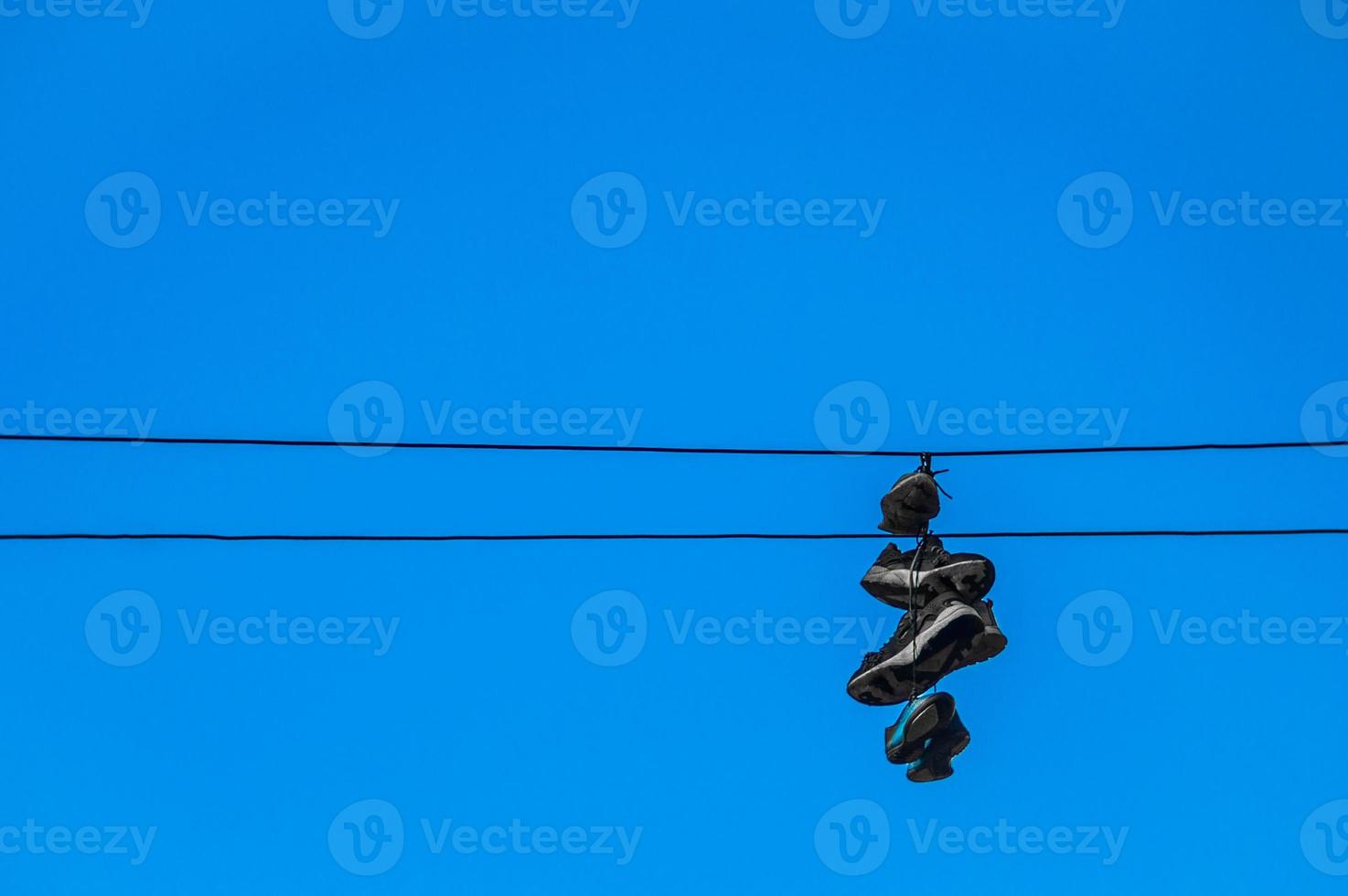 Sneakers hanging on wires against a blue sky photo