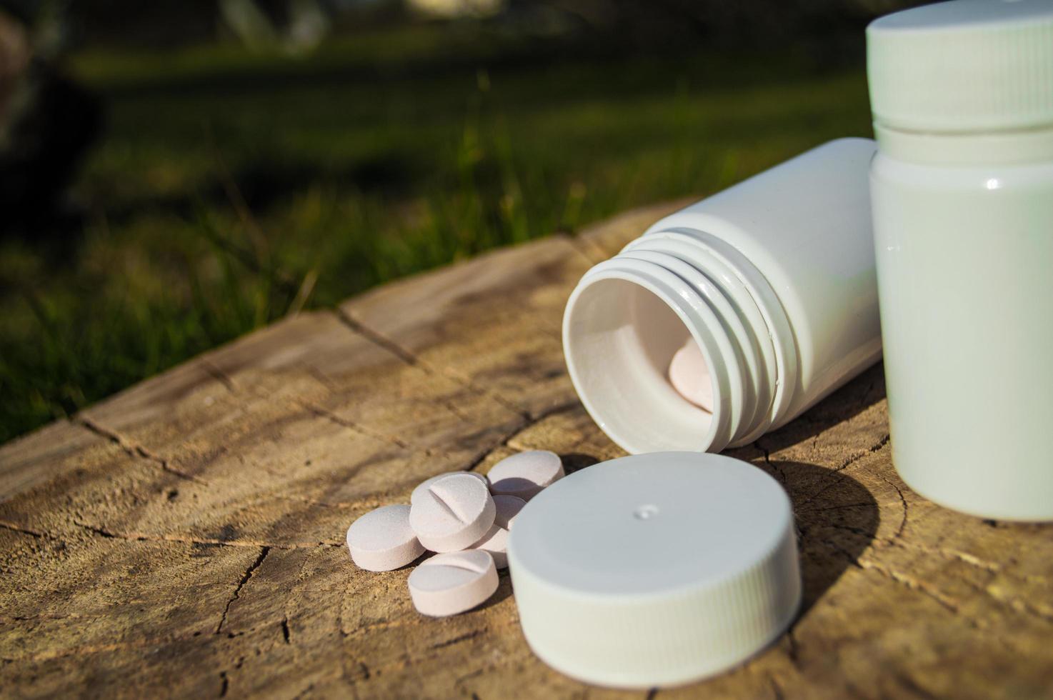 White jar and white pills lie on a stump photo