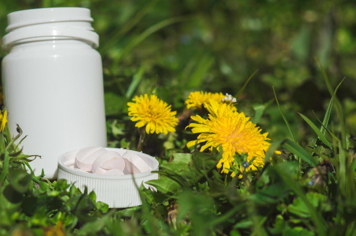 White pills in the grass with flowers photo