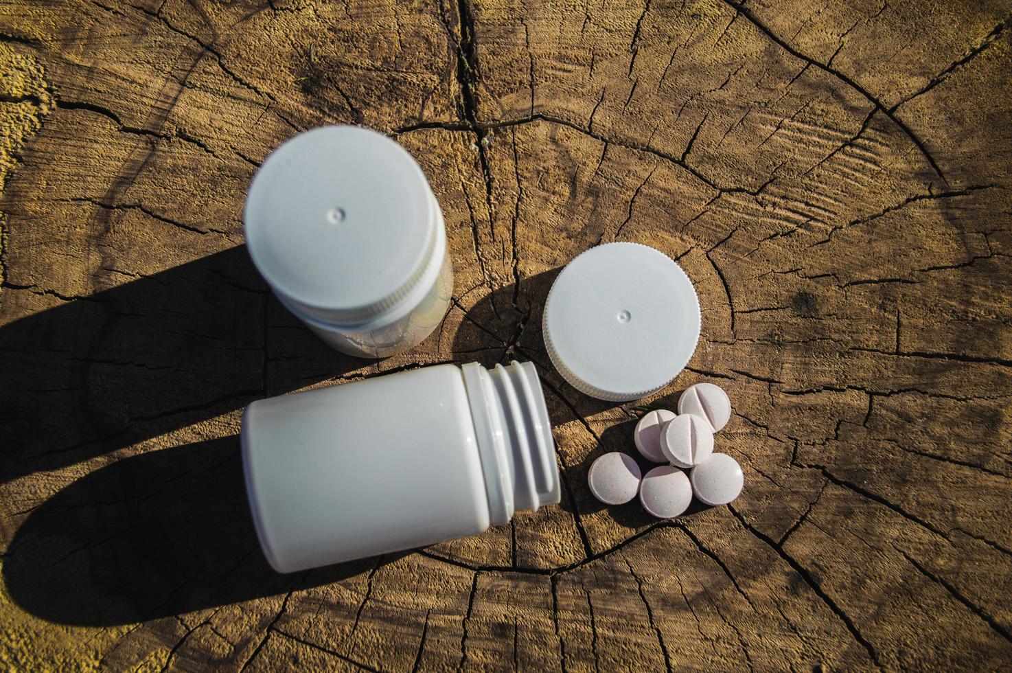 White jar and white pills lie on a stump photo