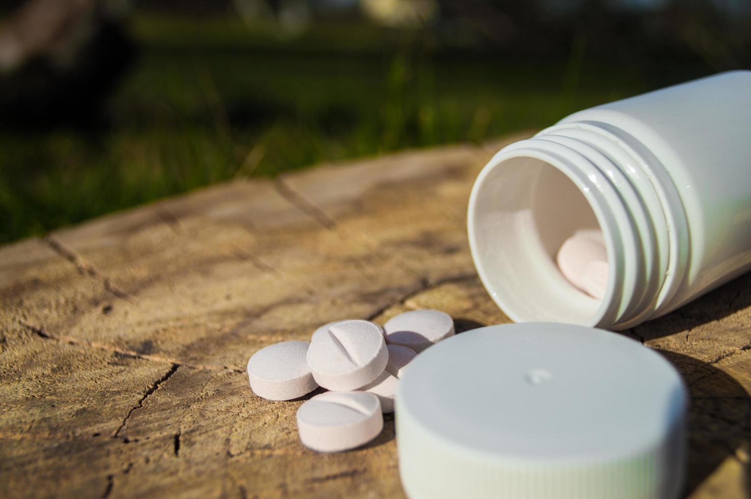 White jar and white pills lie on a stump photo