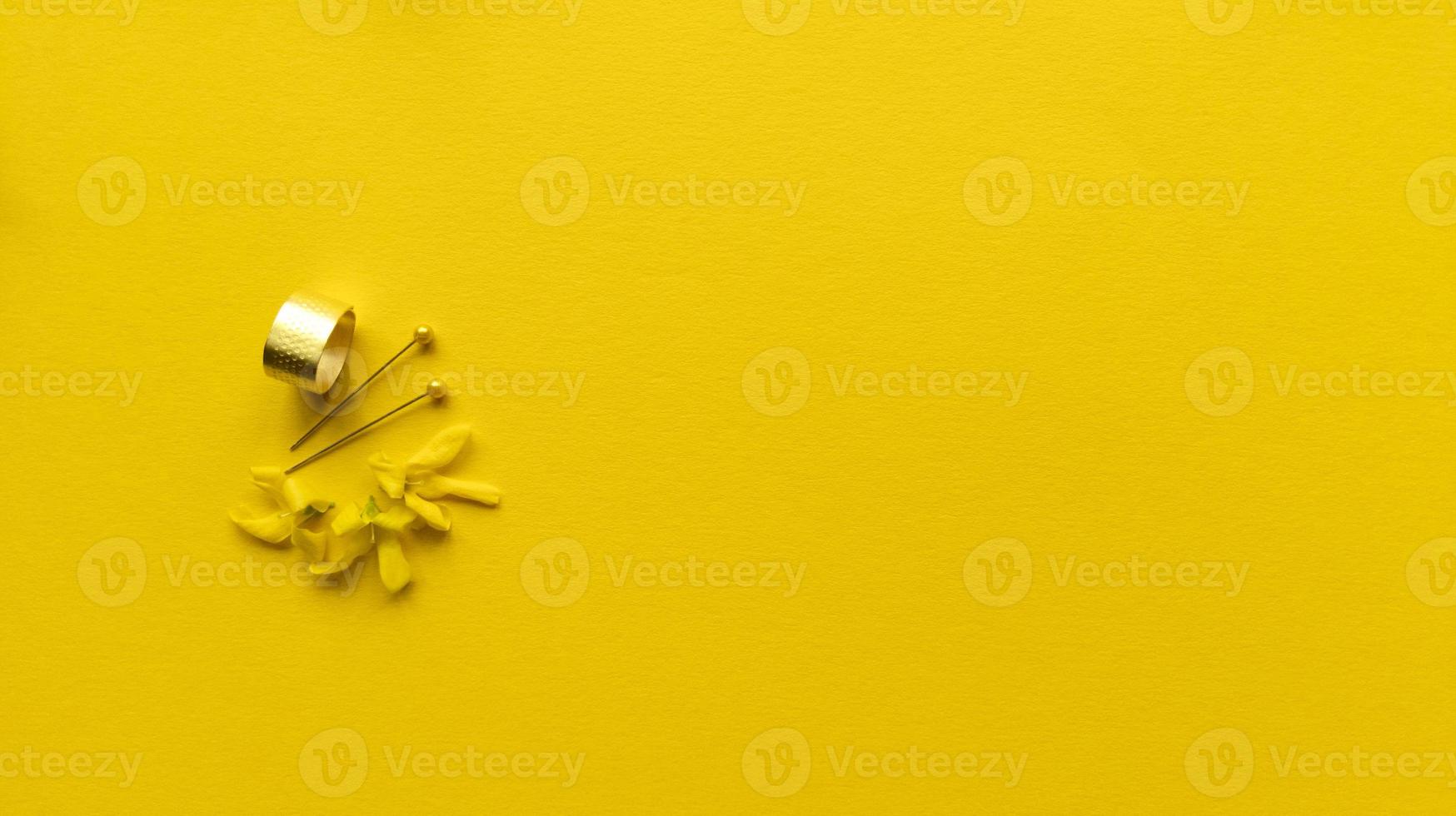 Thimble needles with head and flowers forsythia maluch on yellow background Monochrome simple flat lay with pastel texture Fashion eco concept Stock photo