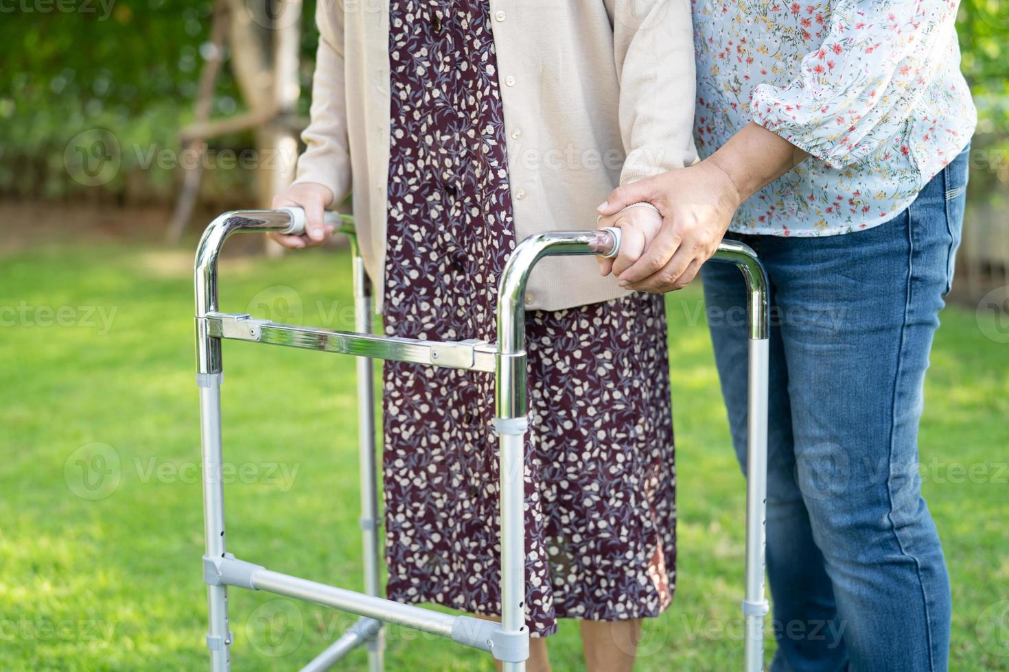 Help and care Asian senior or elderly old lady woman use walker with strong health while walking at park in happy fresh holiday photo