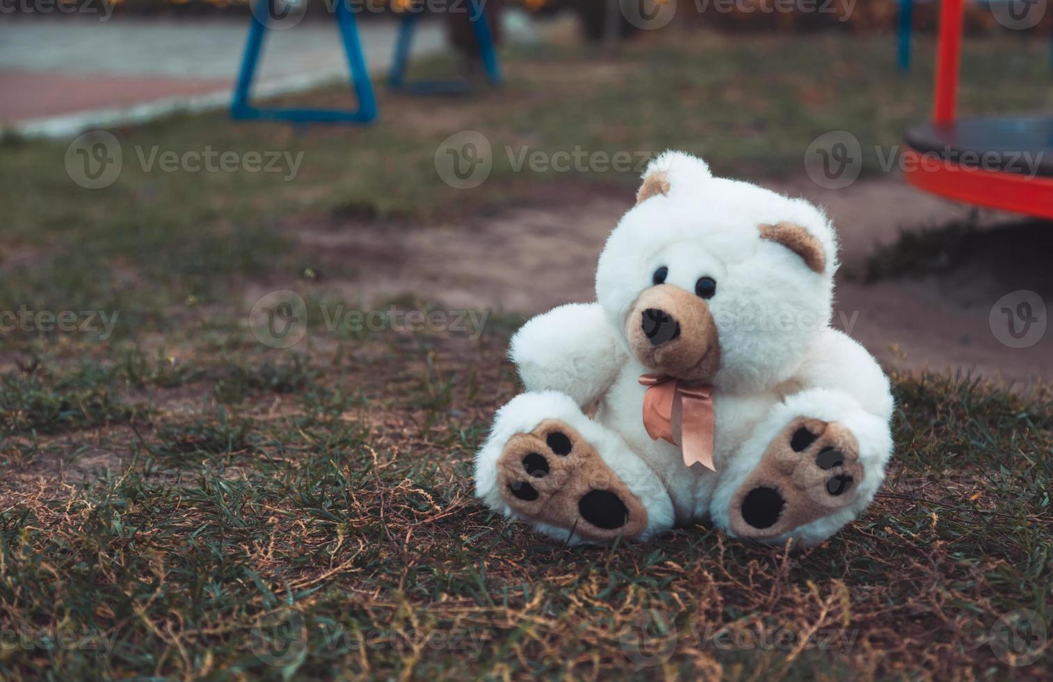 Oso de peluche de felpa suave abandonado sentado en el suelo foto