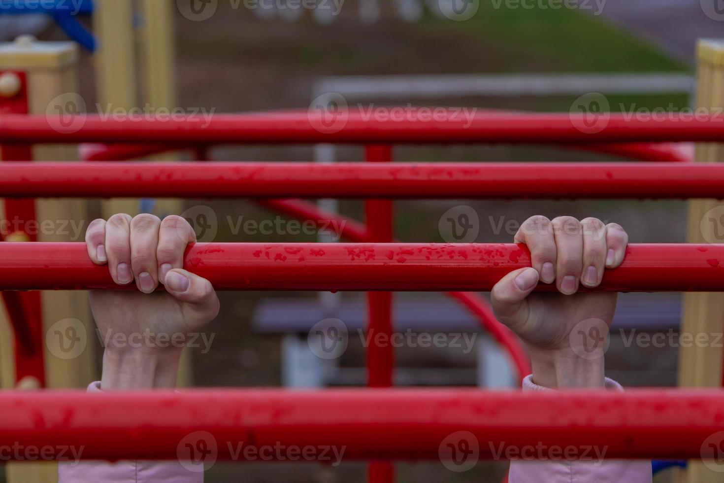 Girl hanging on bar by two hands on outdoor park photo