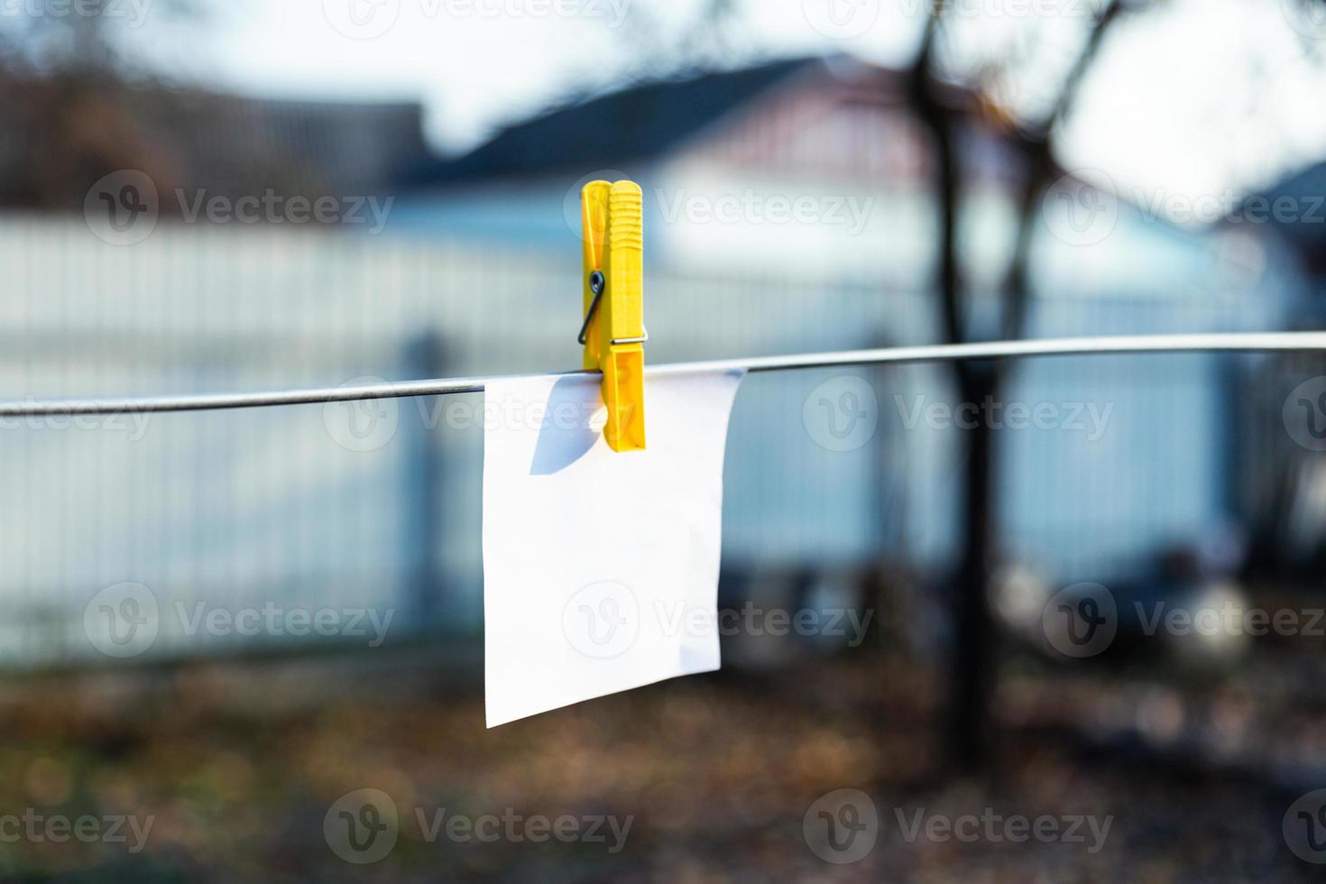 una hoja de papel blanca sujeta con una pinza de ropa amarilla foto