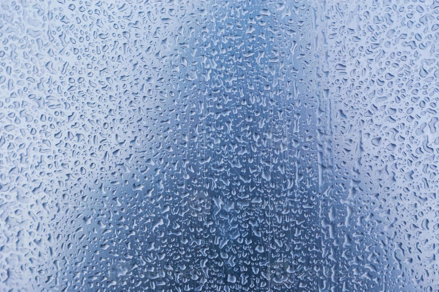 Gotas de lluvia sobre fondo de cristal azul con textura foto