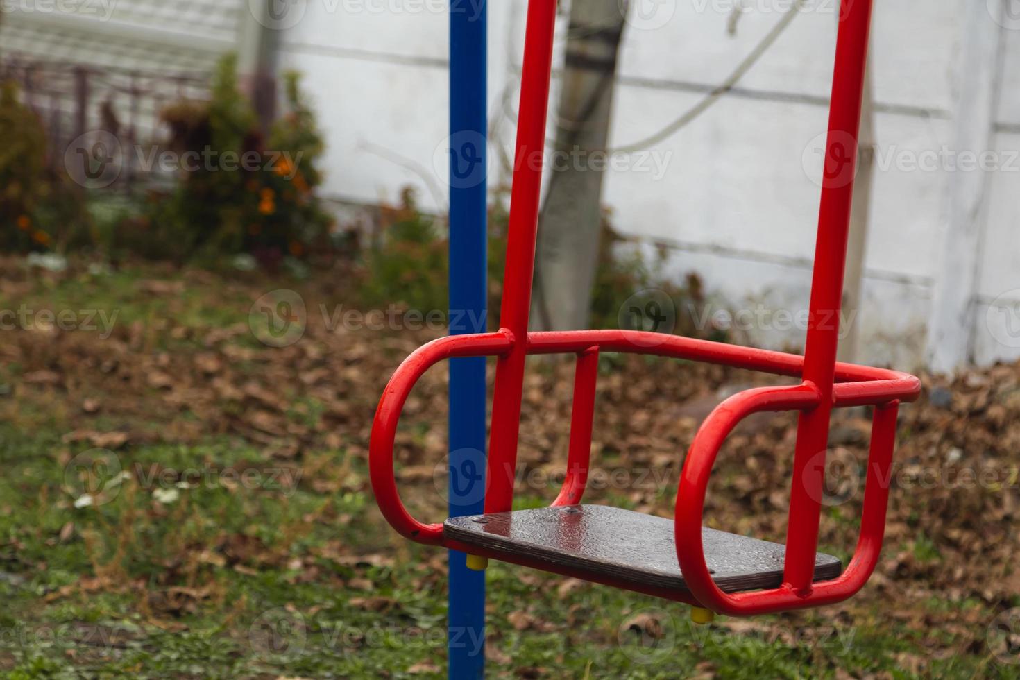 Empty red children's swing photo